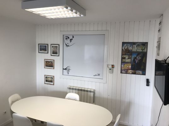 salle de réunion prête à vous accueillir Salvador Dali. Chaises blanches, table blanche, tableau blanc et télévision noire