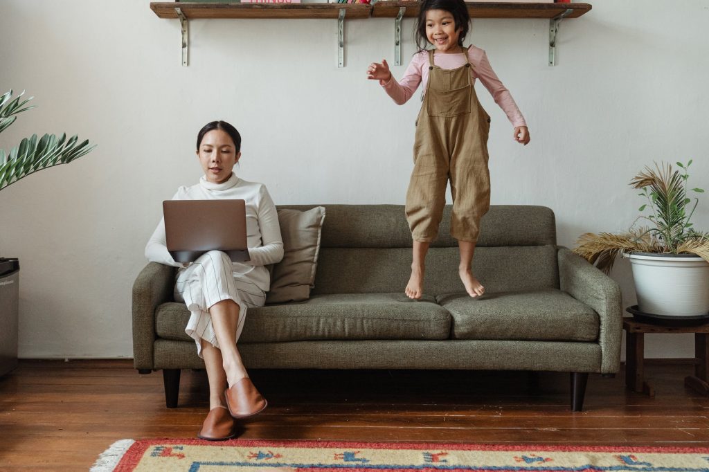 Mère et enfant sur un canapé pendant que la mère fait du télé-travail